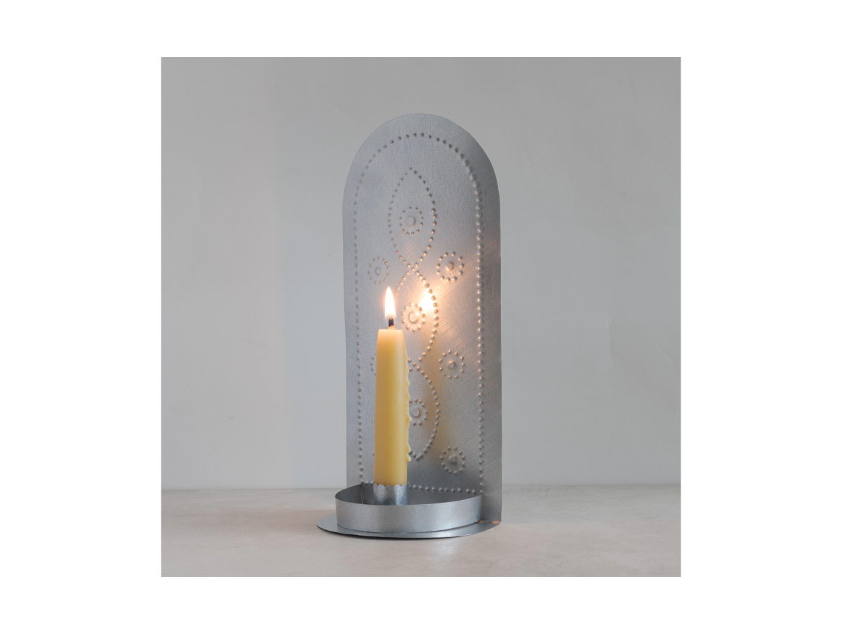 Handmade tin taper candleholder with lit candle and pierced floral pattern