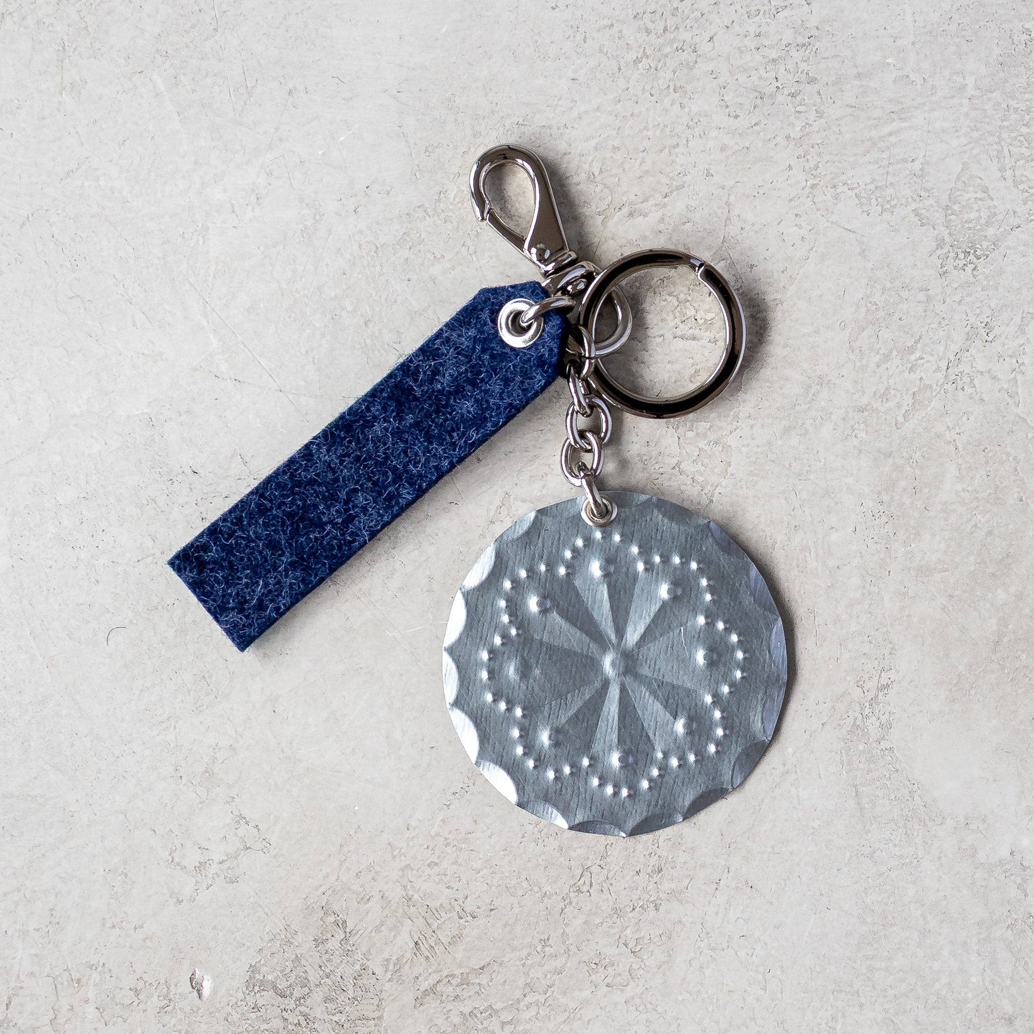 Accent Lever Bag Charm with indigo felt tag, nickel swivel clip, and tin rosette charm.