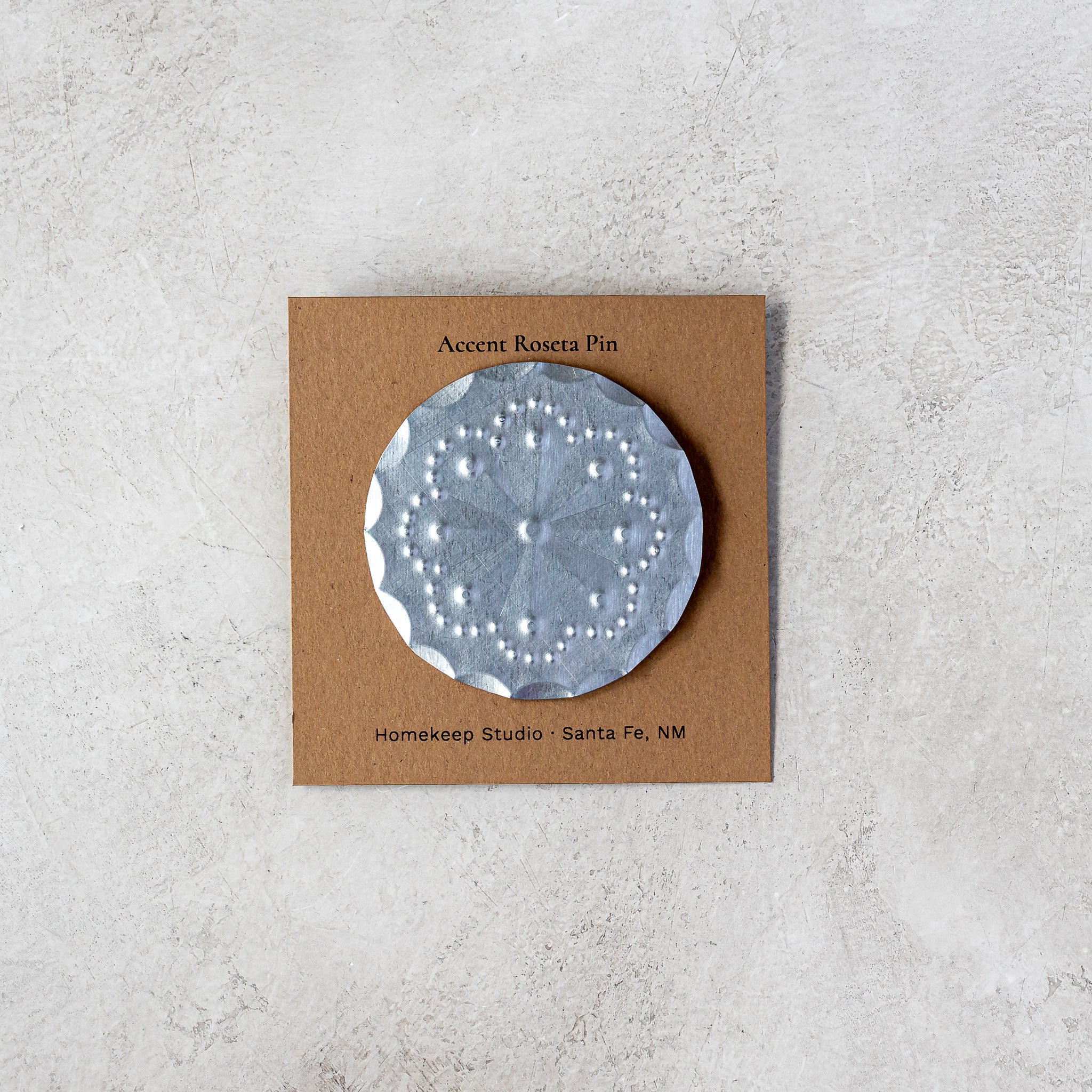 Accent Roseta Pin on kraft backing card, flat lay view on stone surface.