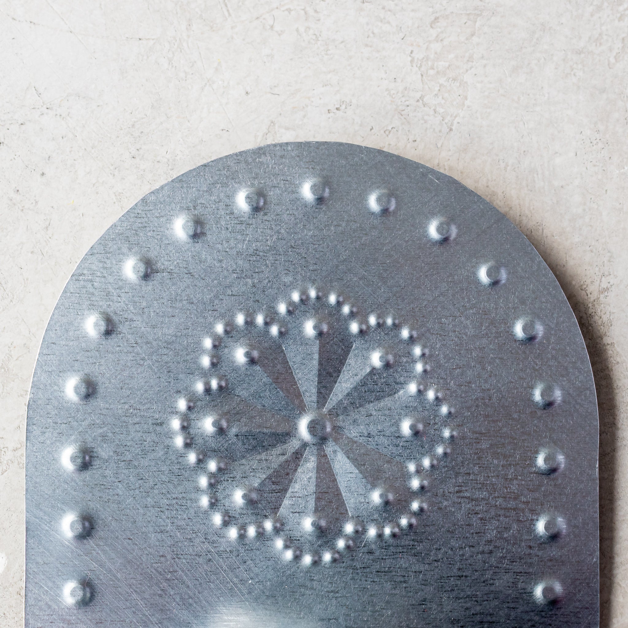 Close-up of hand-punched rosette pattern on the Luz Roseta Tealight Holder in tin.