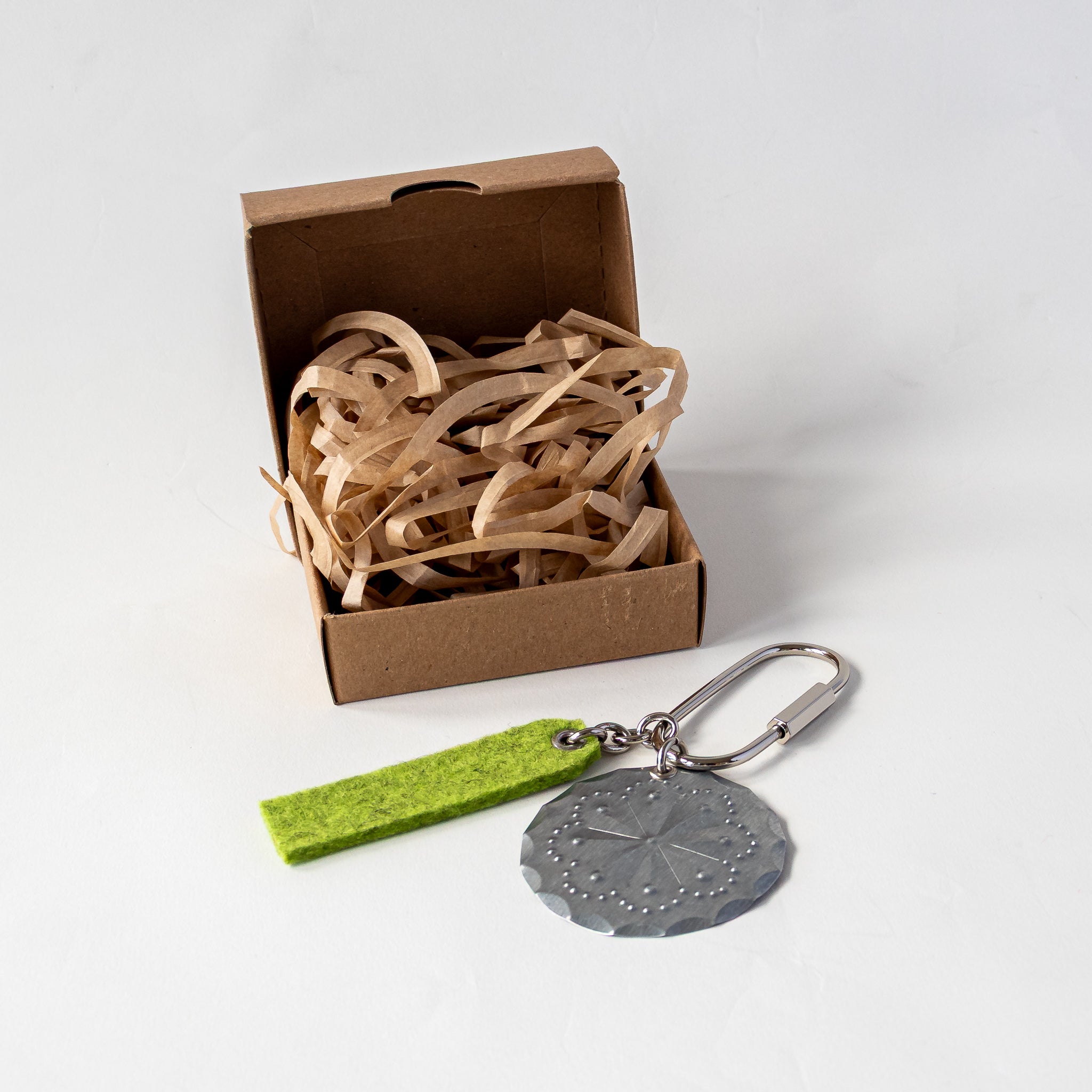 Accent Oval Key Ring shown beside kraft jewelry box with paper fill for gift packaging.