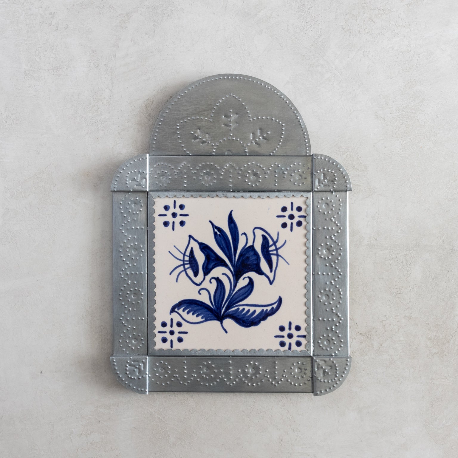 Decorative tinwork framed tile with blue floral design on a white background