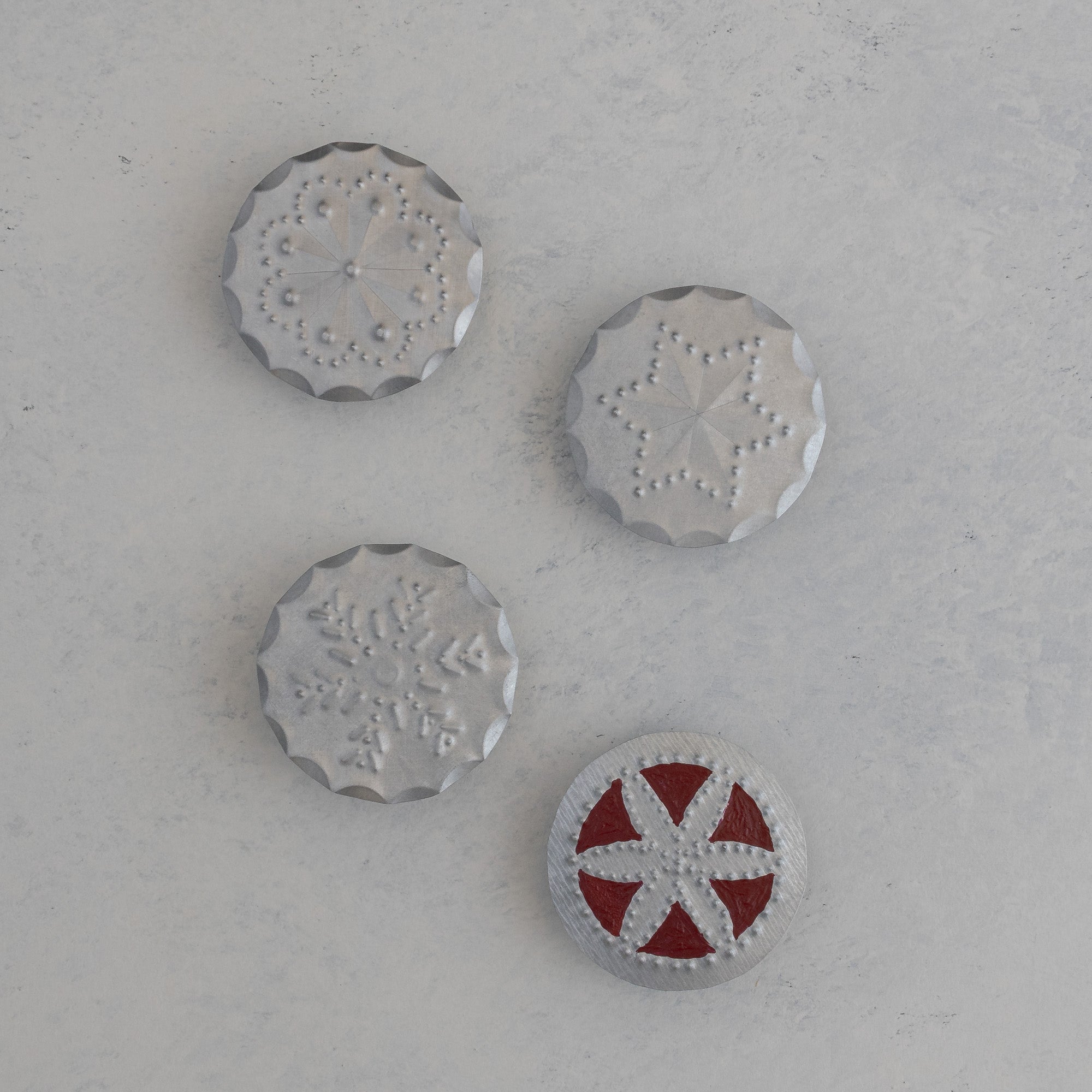 Four hand punched tin bandana slides, Roseta, Estrella, Nieve, and a red painted variant, handmade in Santa Fe