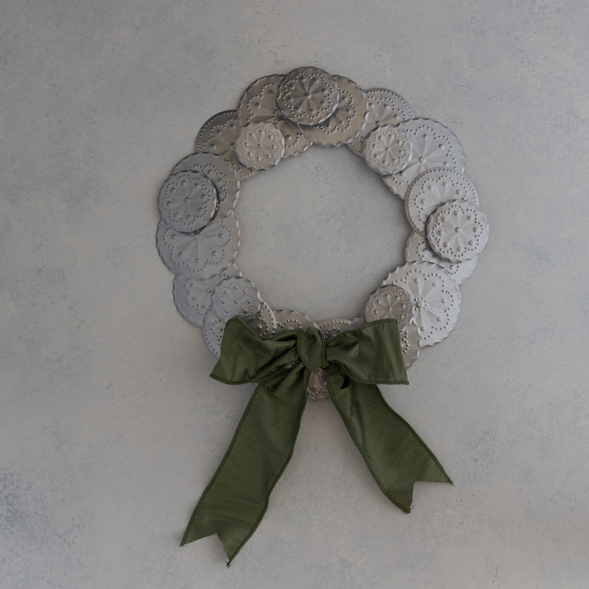 Roseta Corona tin wreath with moss dupioni ribbon bow positioned at the bottom