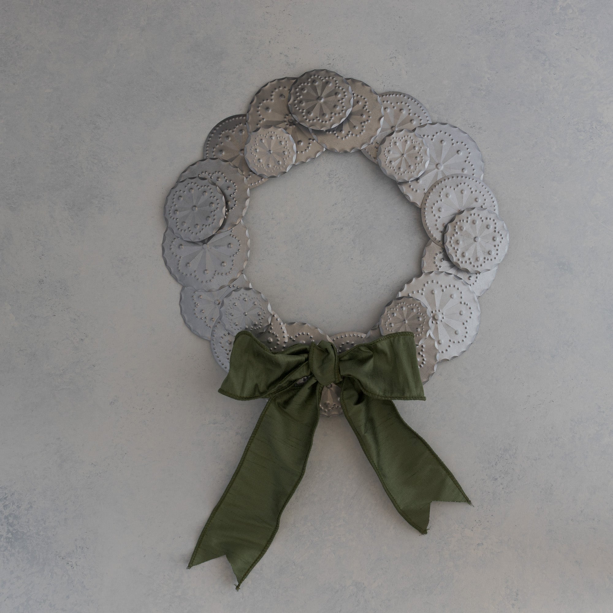Roseta Corona tin wreath with moss dupioni ribbon bow positioned at the bottom