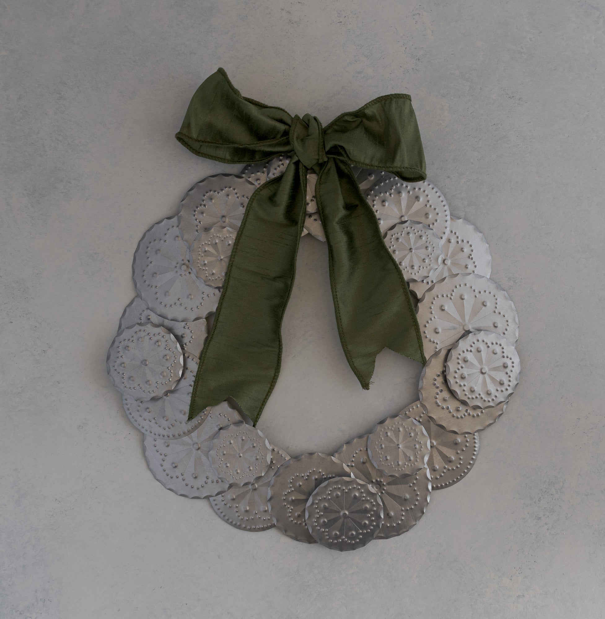 Roseta Corona tin wreath with moss dupioni ribbon bow positioned at the top