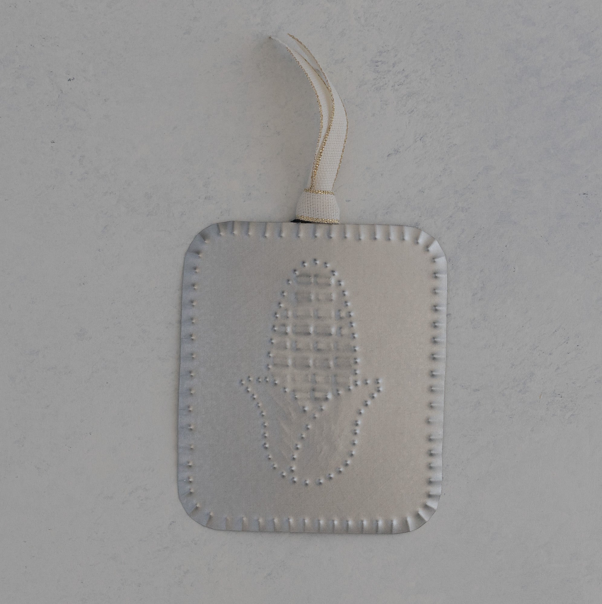 Hand punched tin maize milagro ornament with scalloped edge and gold trimmed ivory ribbon, handmade in Santa Fe