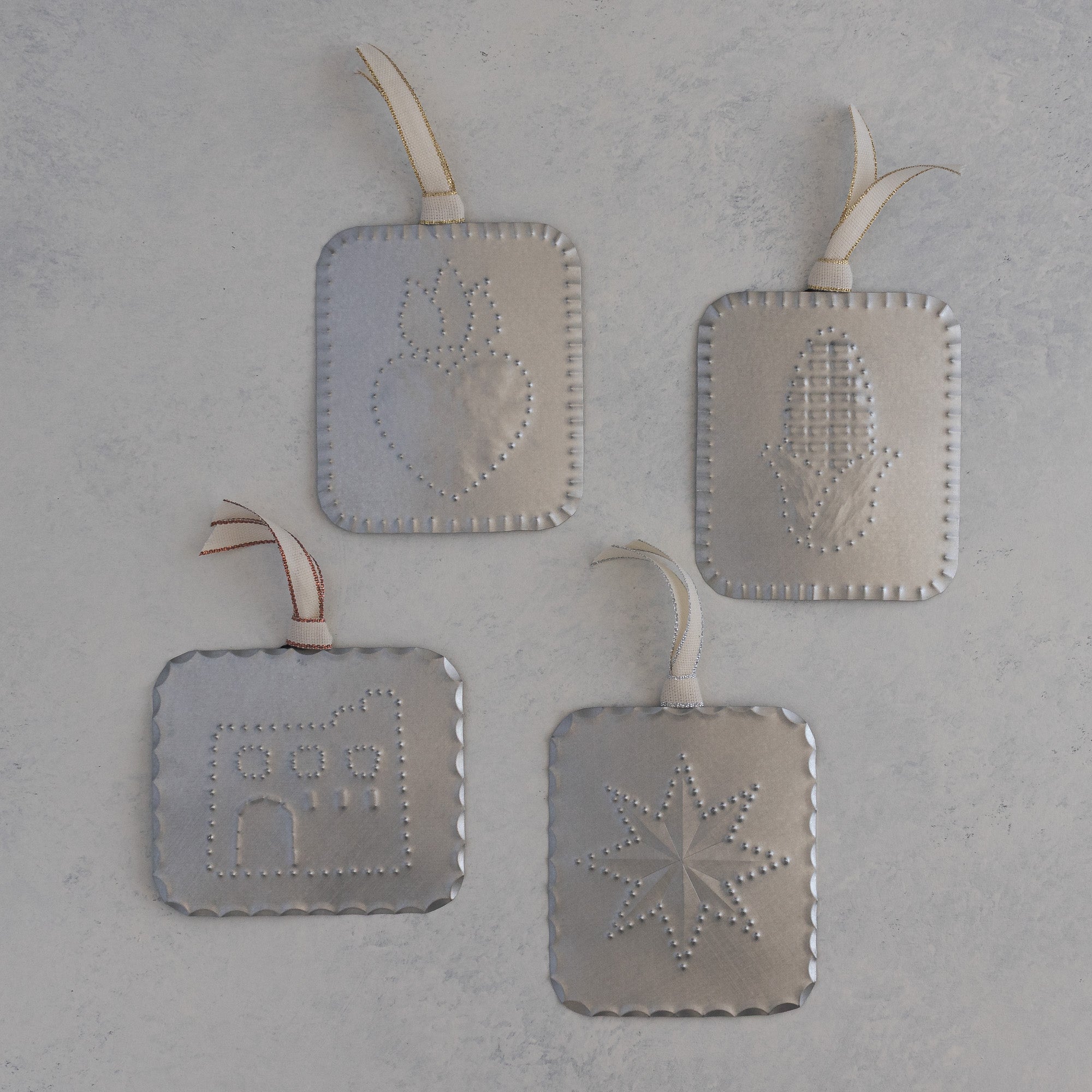 Four small hand punched tin milagros, sacred heart, maize, adobe house, and star, each with a ribbon, handmade in Santa Fe
