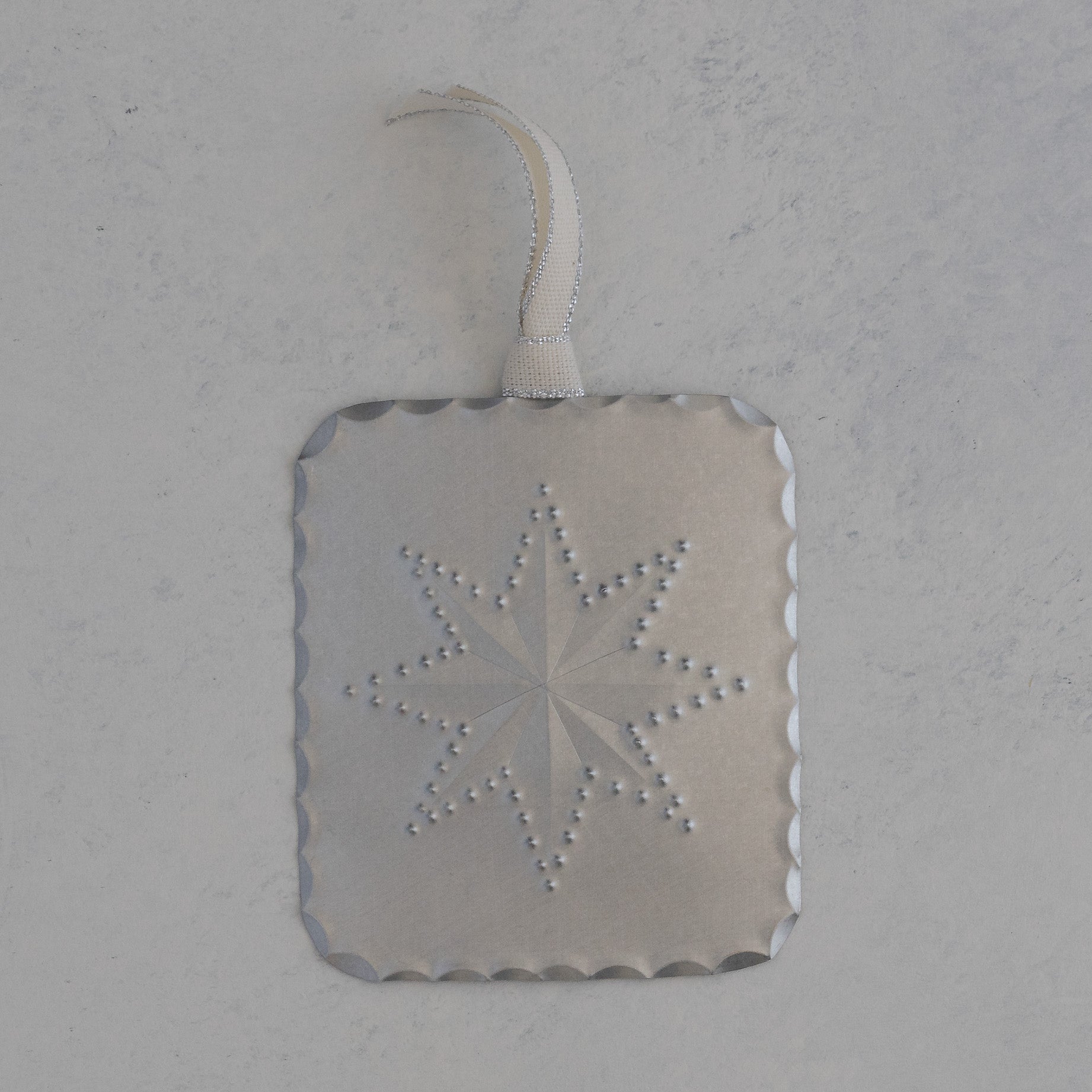 Hand punched tin star milagro ornament with scalloped edge and ivory ribbon, handmade in Santa Fe