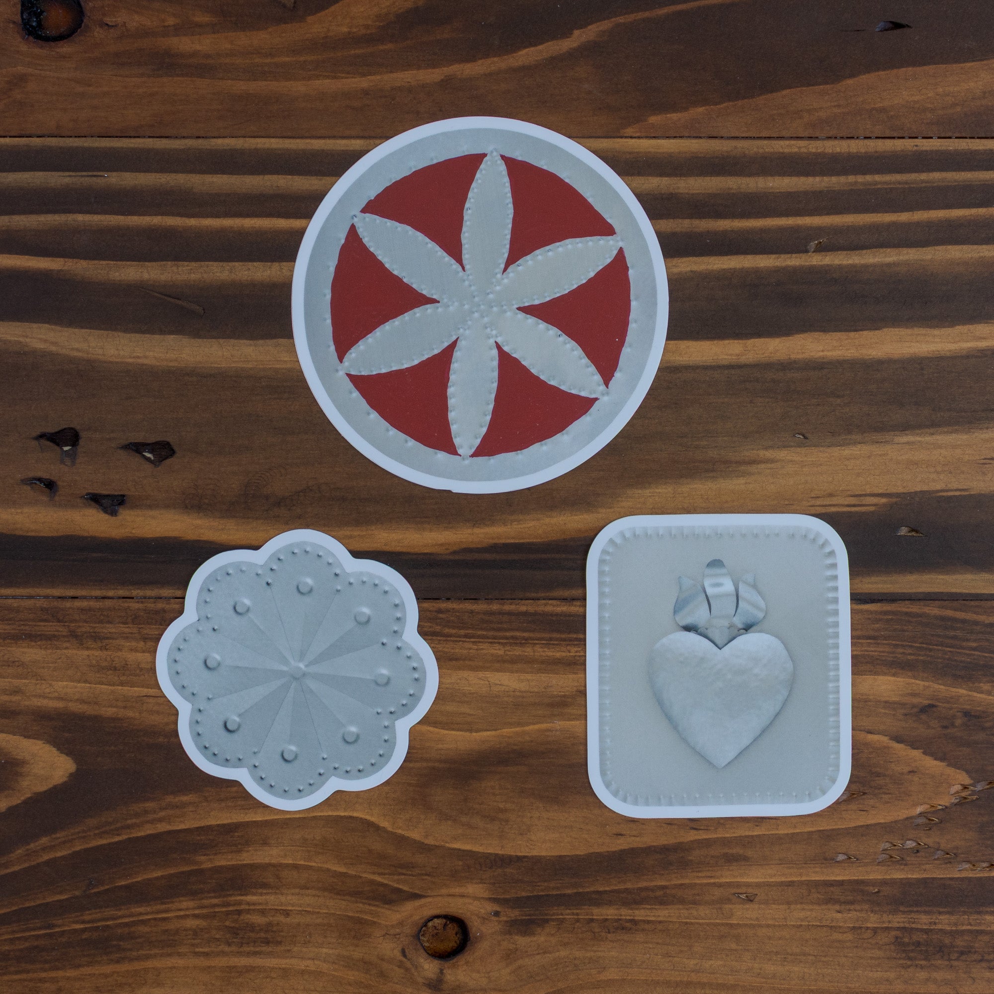 hree Homekeep Studio stickers on dark wood — Flor circle at top, Roseta scallop and Sacred Heart below