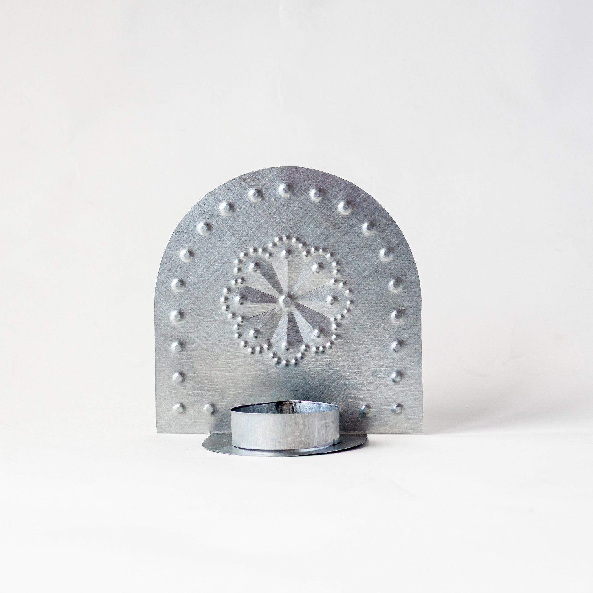 Front view of Luz Roseta Tealight Holder with round rosette punch pattern and candle cup.
