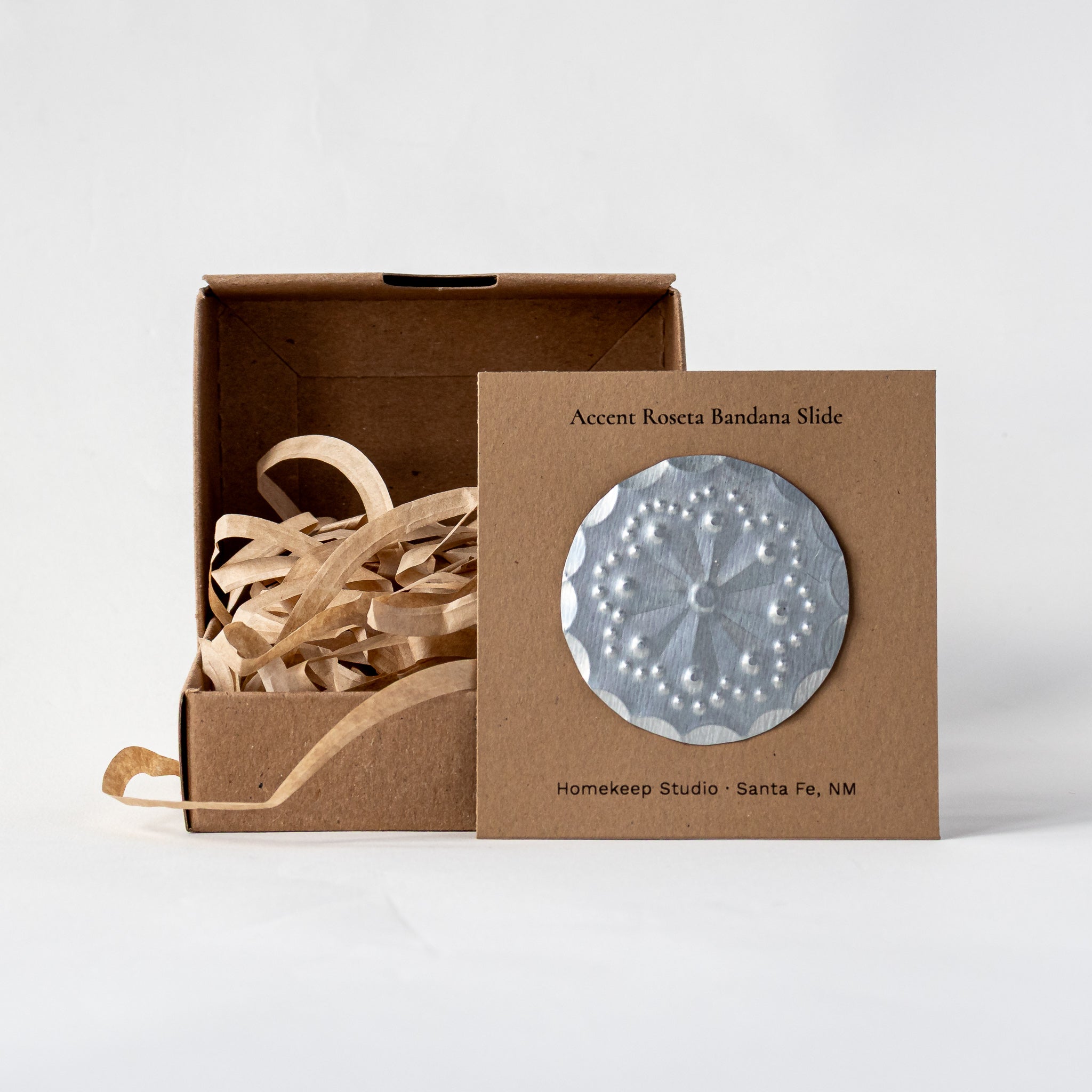 Roseta bandana slide displayed on kraft card packaging with shredded paper filler in a kraft gift box.