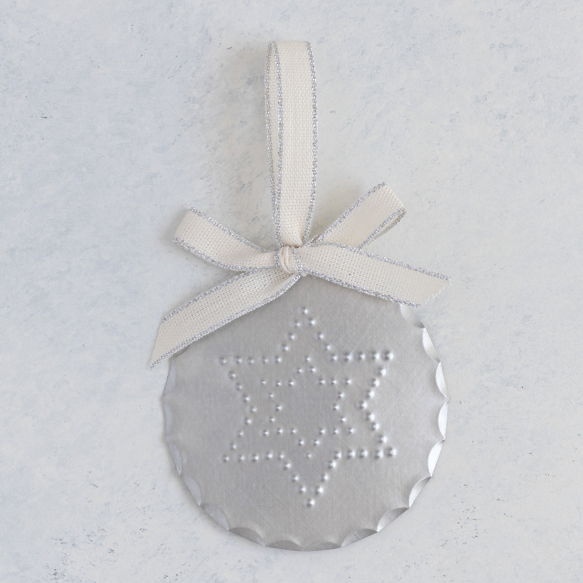 Round hand-punched tin ornament with a Star of David (Magen David) design and cream ribbon hanger