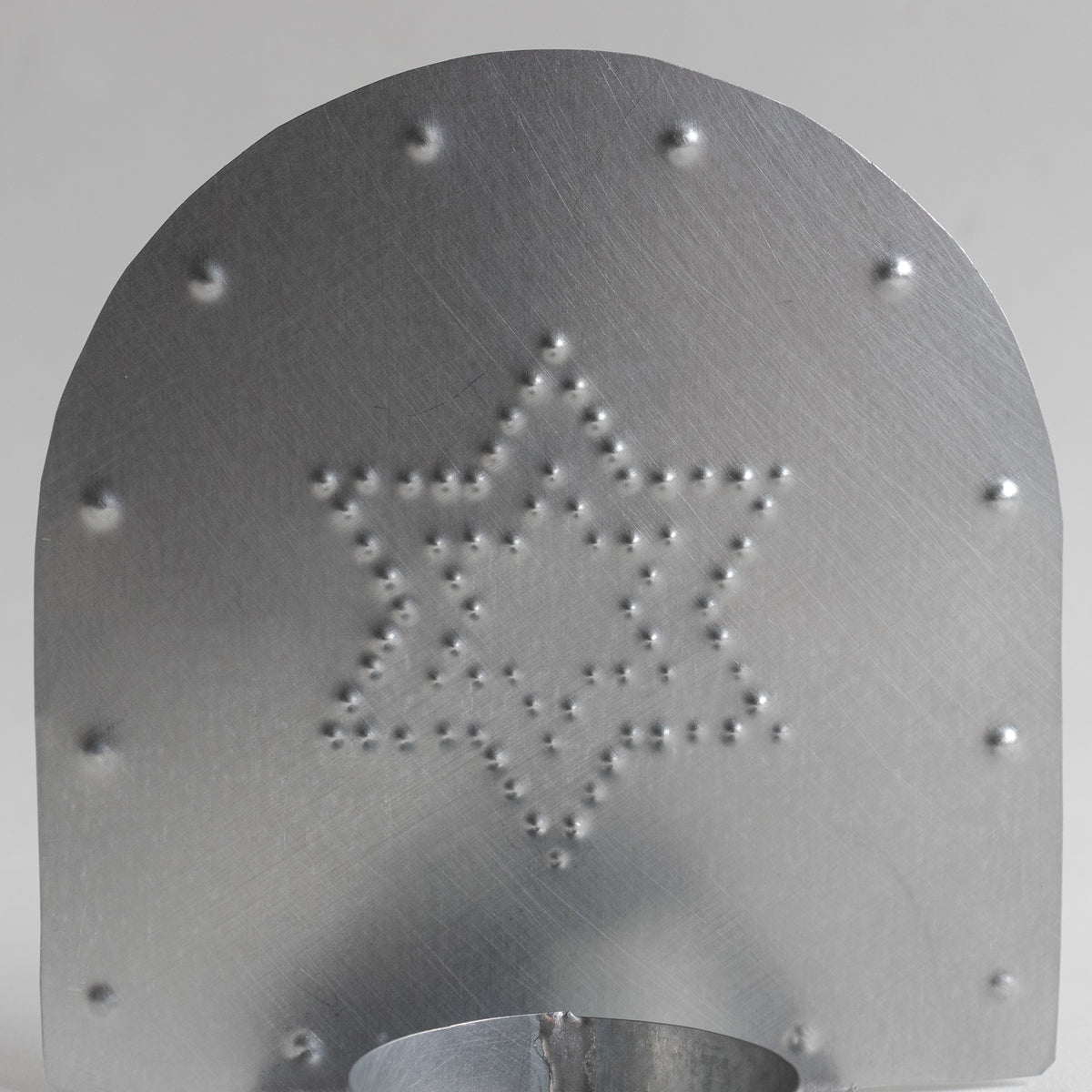 Front of a punched tinwork tealight candleholder with a Star of David motif. 