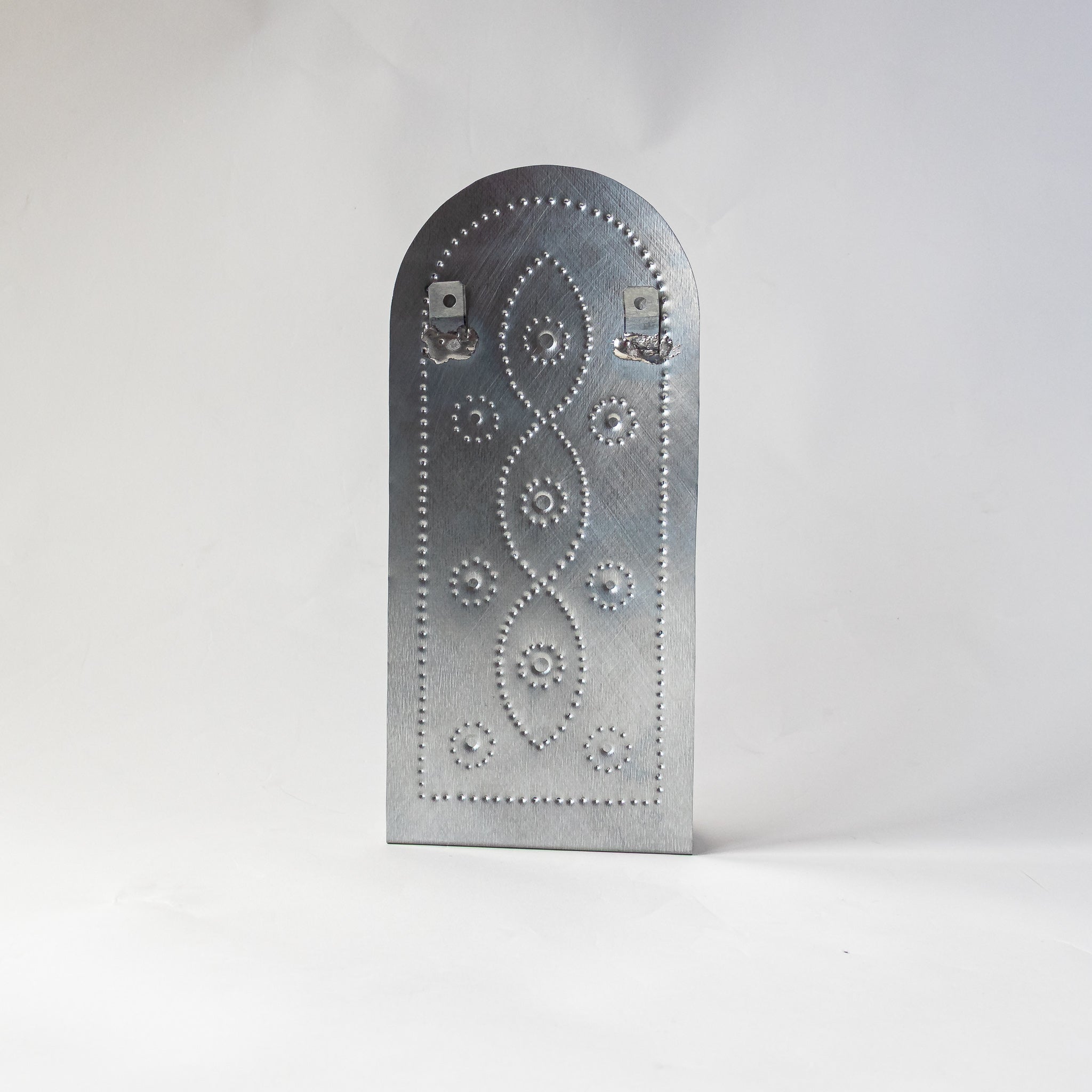 Back view of the Vine taper candleholder, featuring punched tin vine pattern and welded hanging brackets.