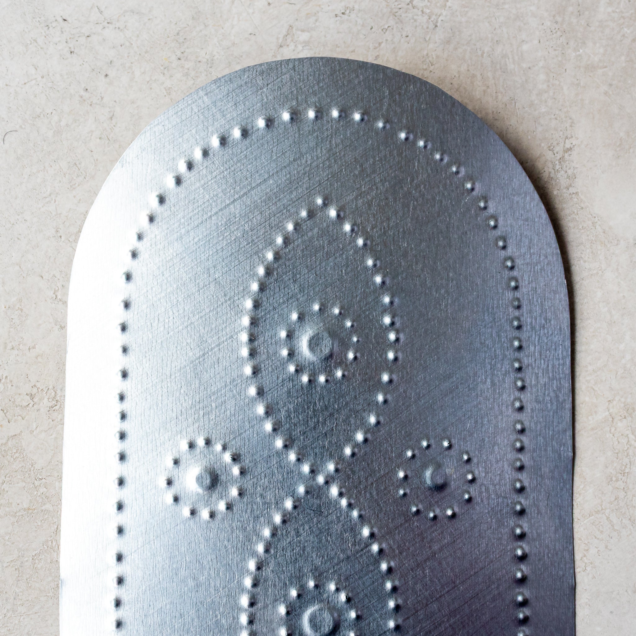 Close-up of hand-punched tin taper candleholder showing vine motif detail