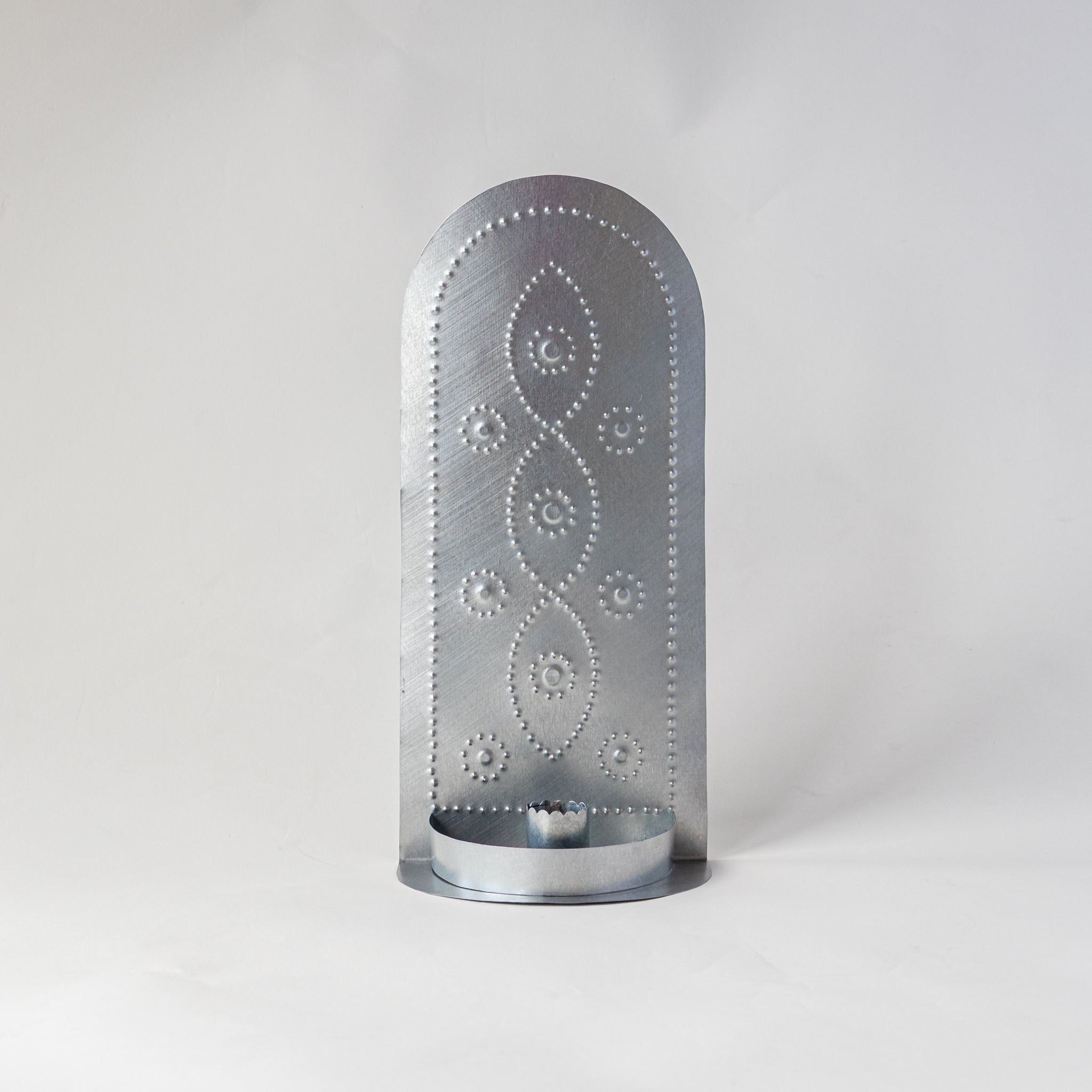 Front view of the Vine taper candleholder with tall punched tin backplate in a vine design and round taper base.