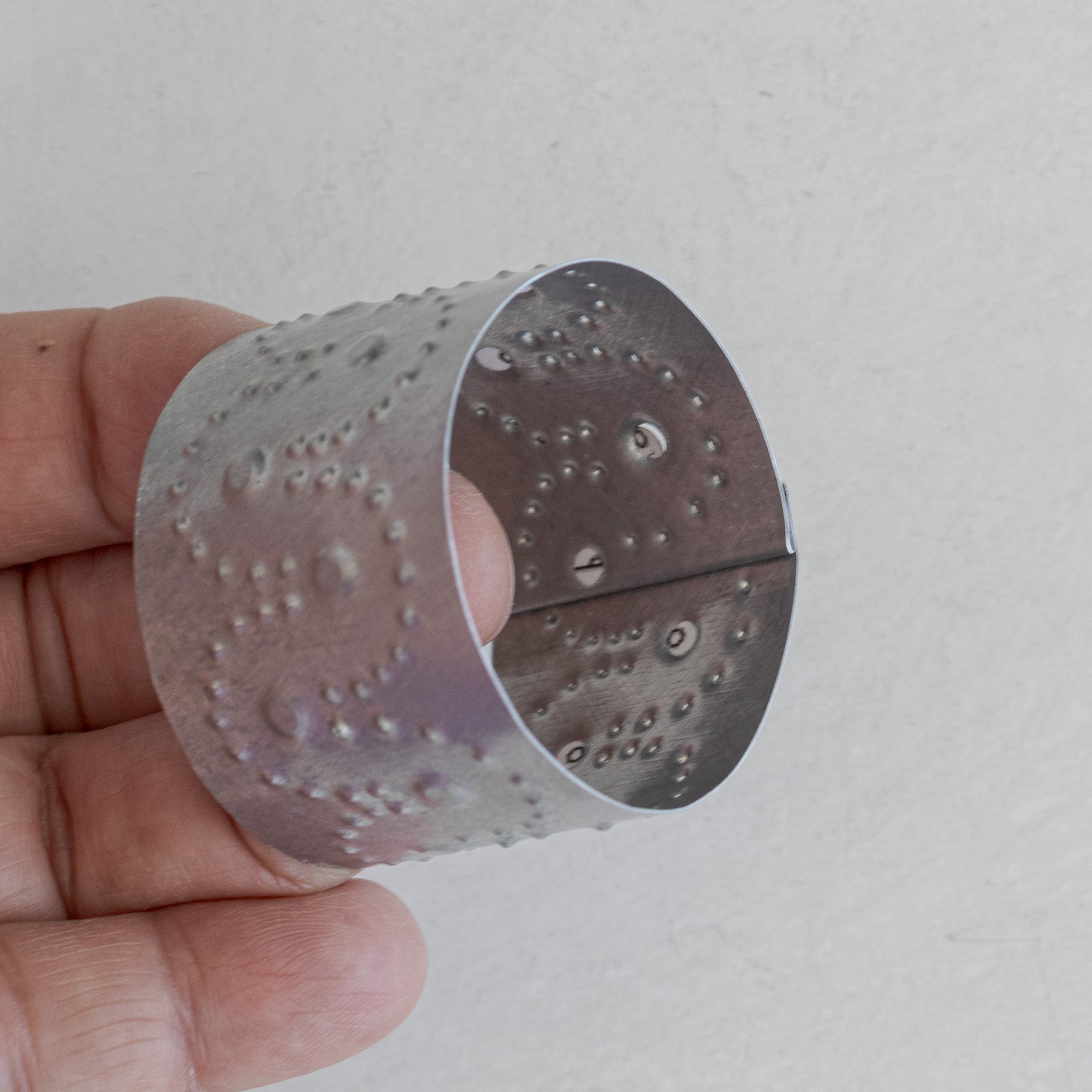 Single Arco tin napkin ring photographed from above showing the circular opening and crimped edge detail, natural tin.
