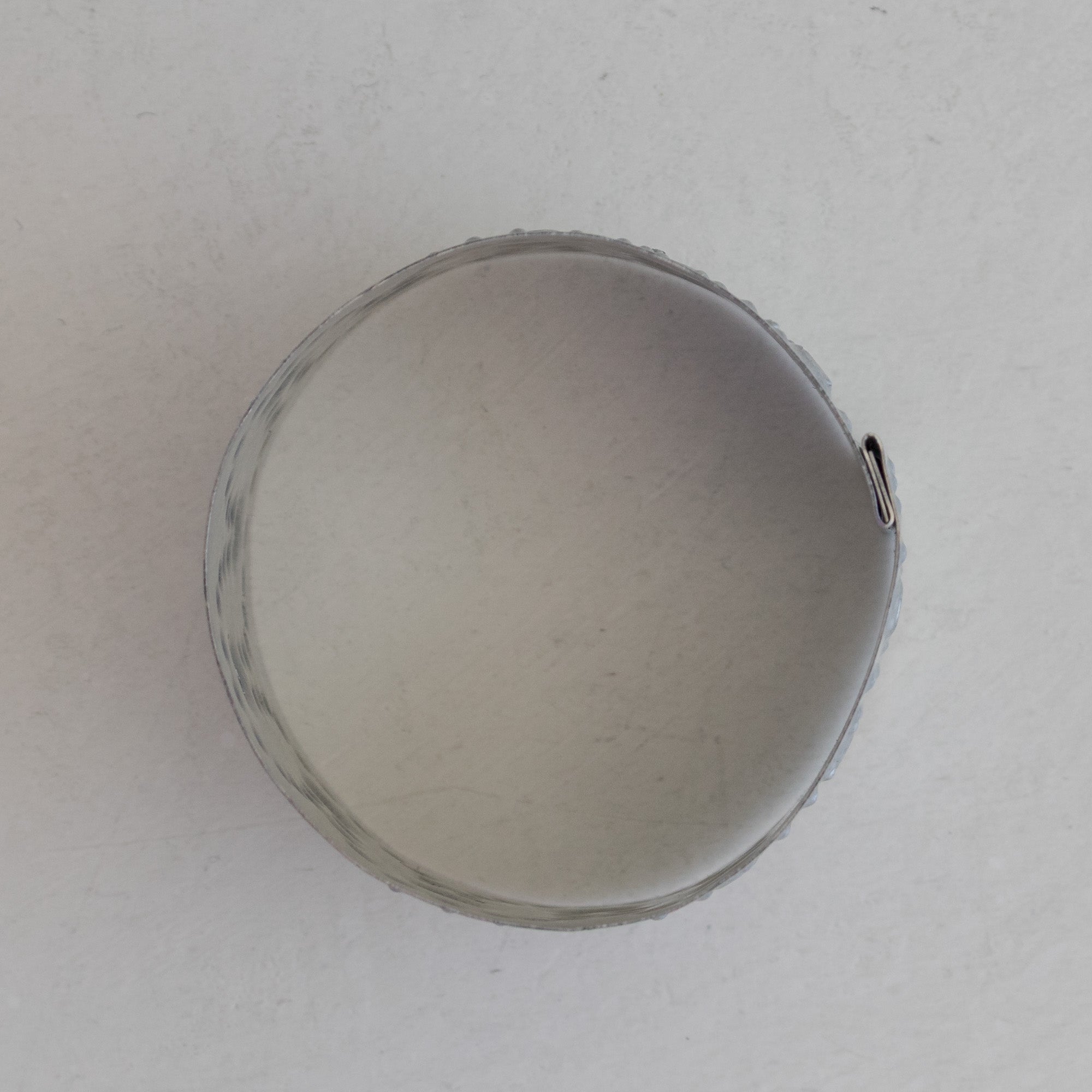 Single Arco tin napkin ring photographed from above showing the circular opening and crimped edge detail, natural tin.