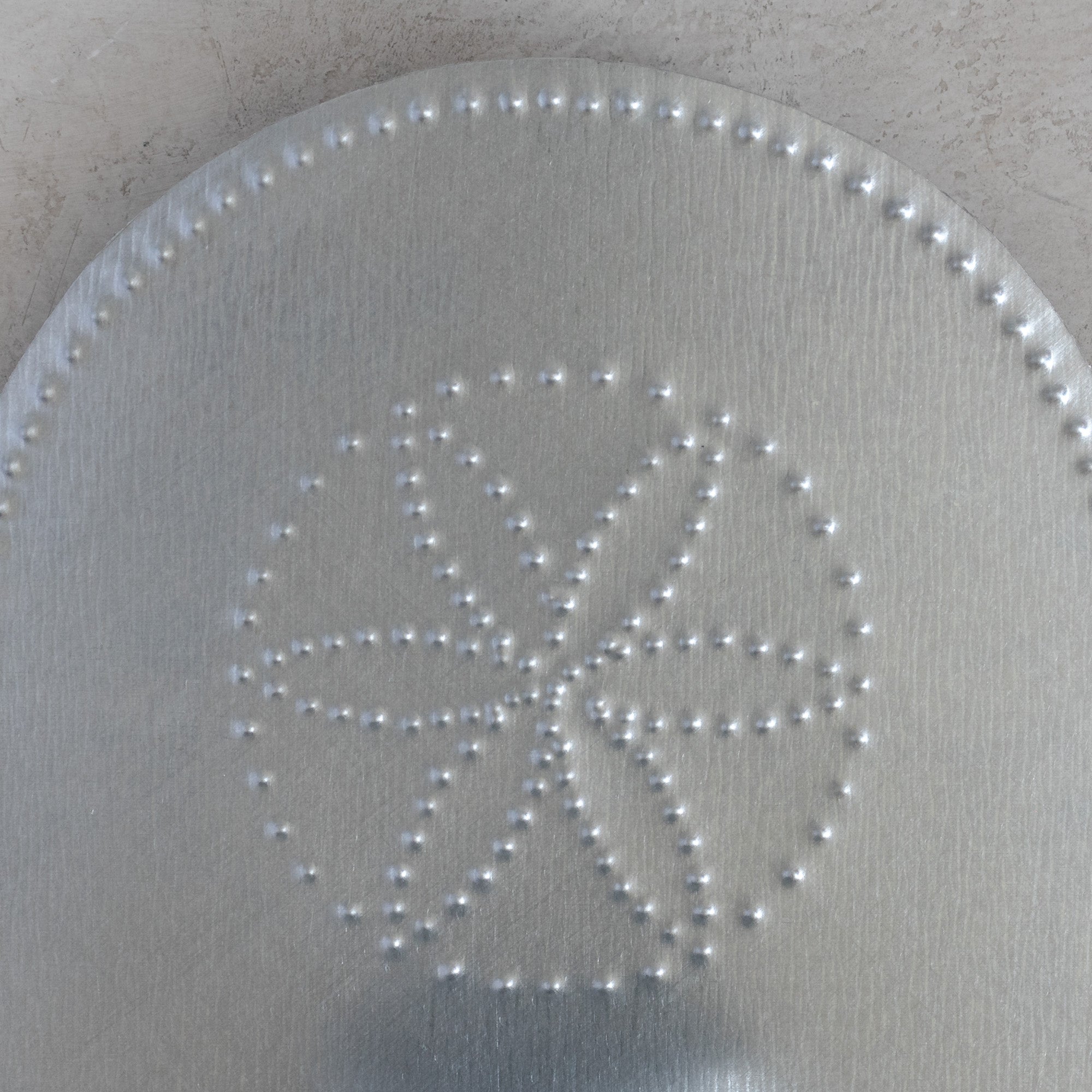 Detail of hand-punched flor pattern in natural tin tealight candleholder