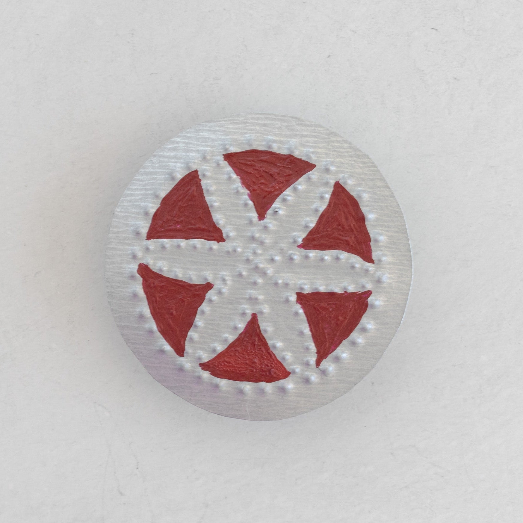 Flor in Wine Bandana Slide front view showing hand-punched floral motif with wine painted negative space on a natural tin disc with dot-punched border.