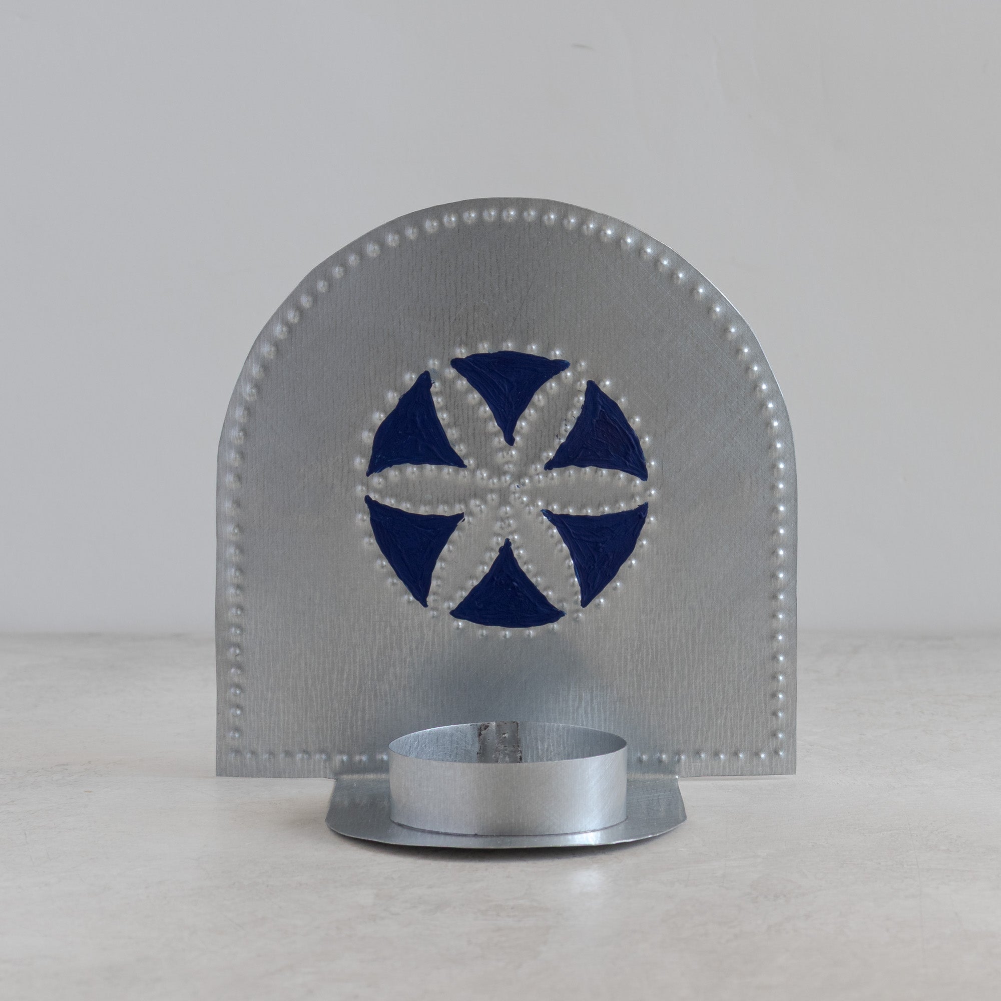 Hand-punched tin tealight candleholder with blue painted rosette motif on light background