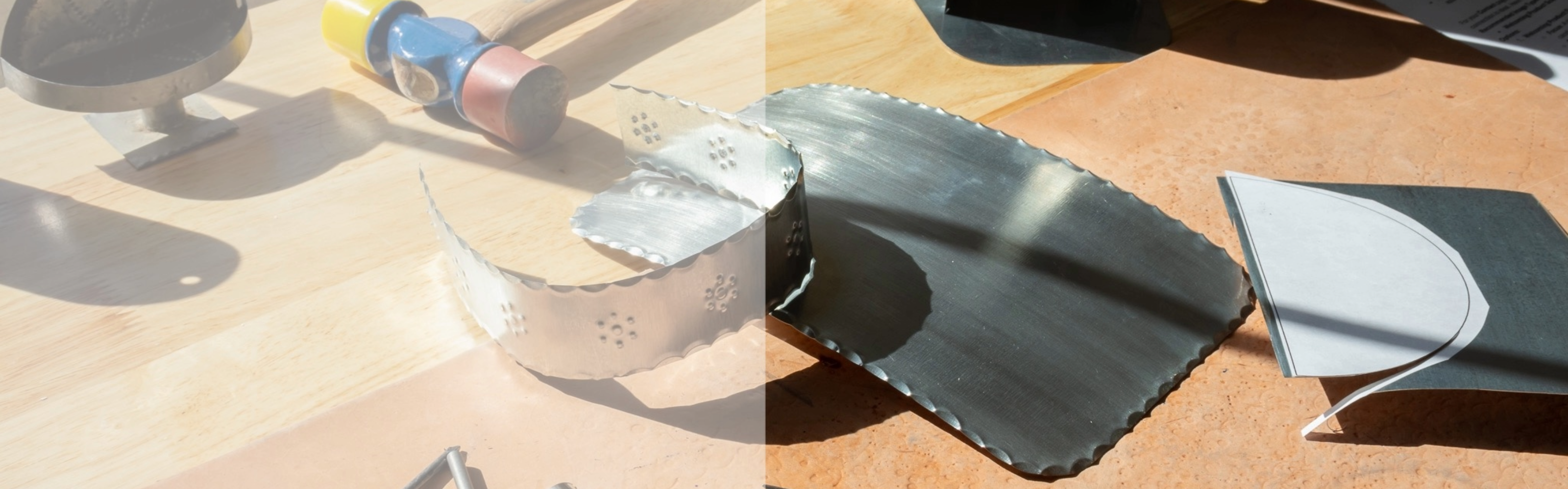 Handcrafted tin pieces and tools on a studio workbench.