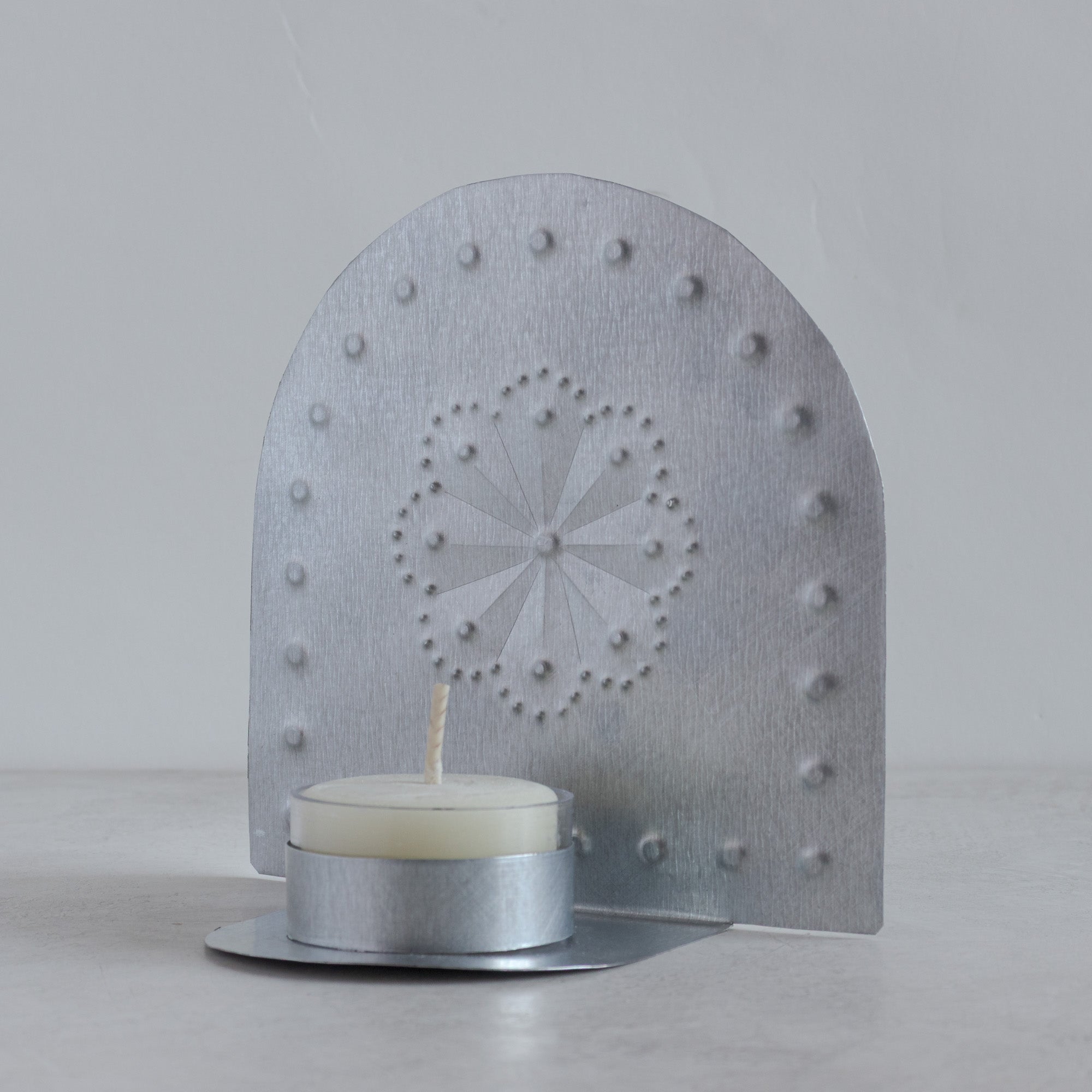 Angled view of handmade Luz Roseta tin tealight candleholder with punched roseta pattern