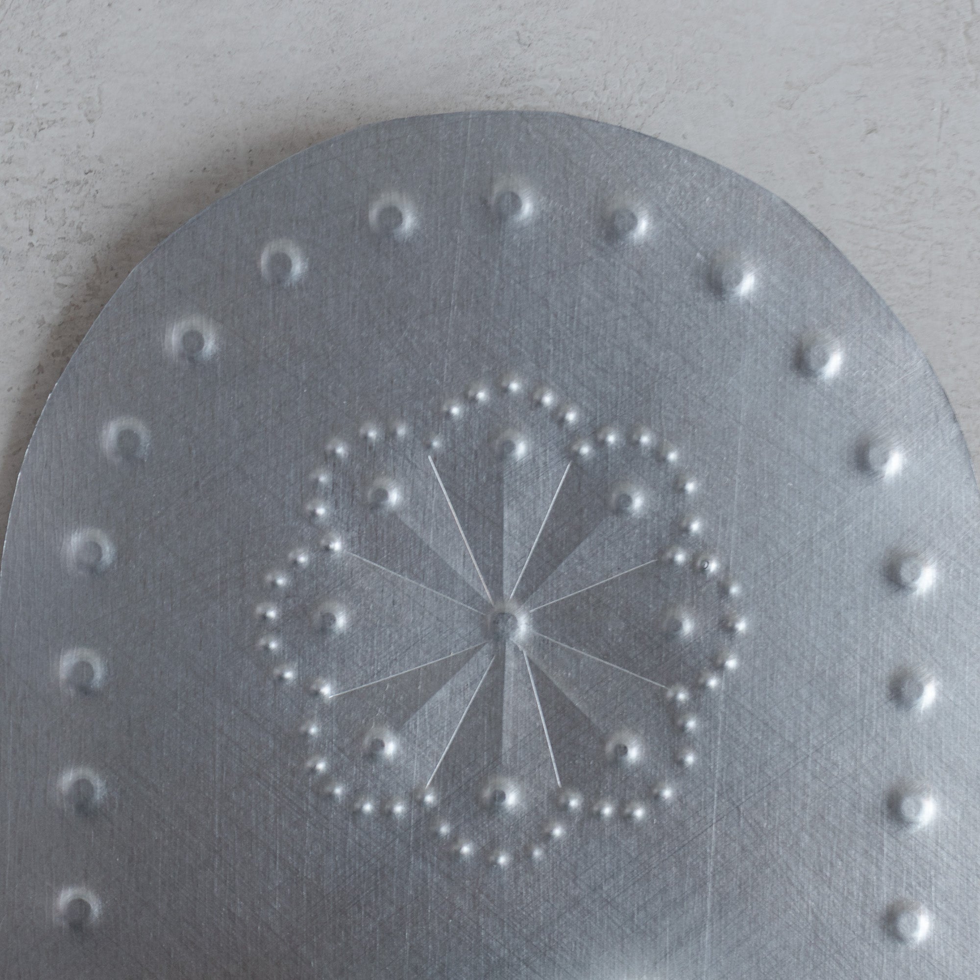 Close-up of hand punched roseta pattern on Luz Roseta tin tealight candleholder