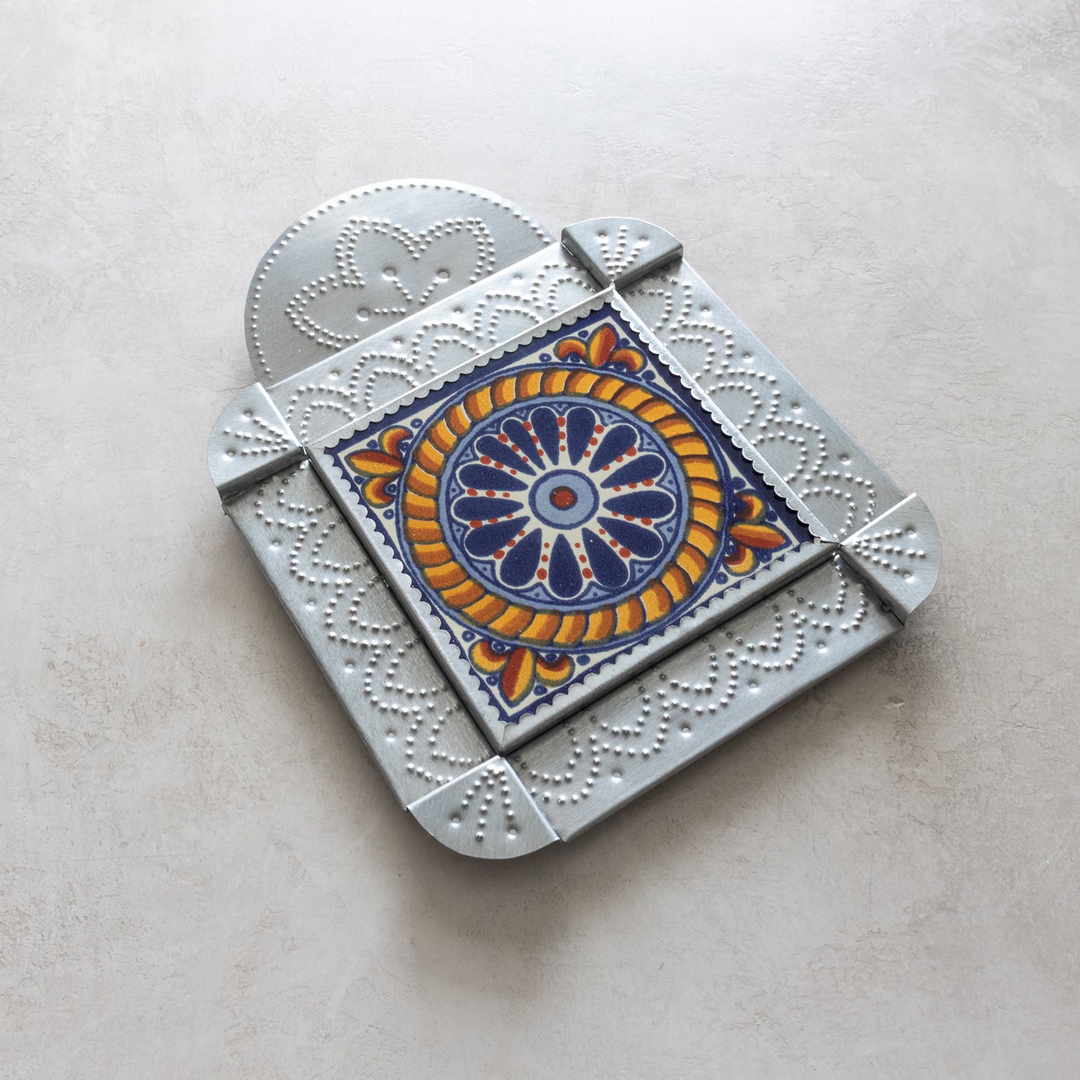 Decorative metal tinwork frame with a colorful circular design on a light gray background