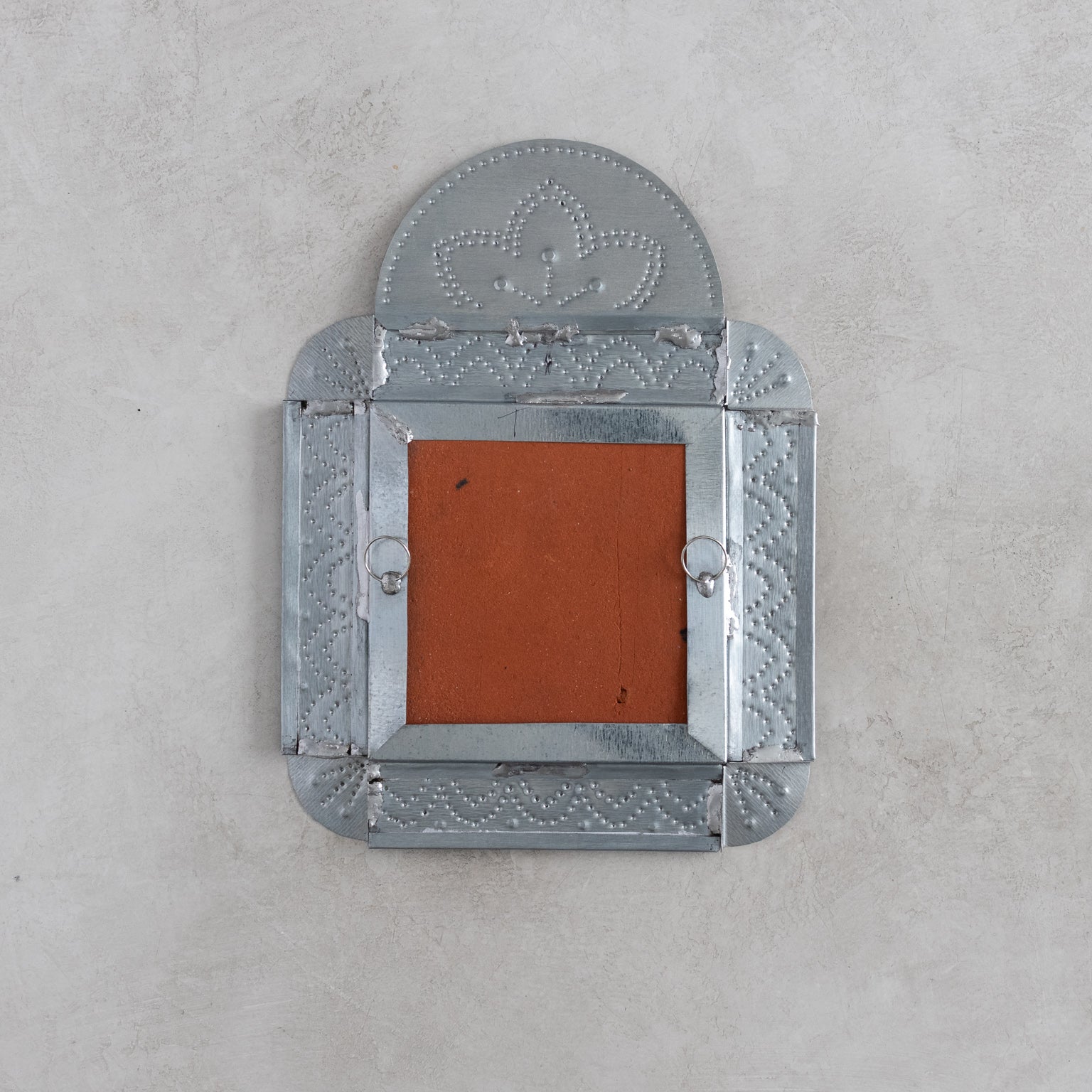 Decorative tinwork wall decor back with hanger on a gray background