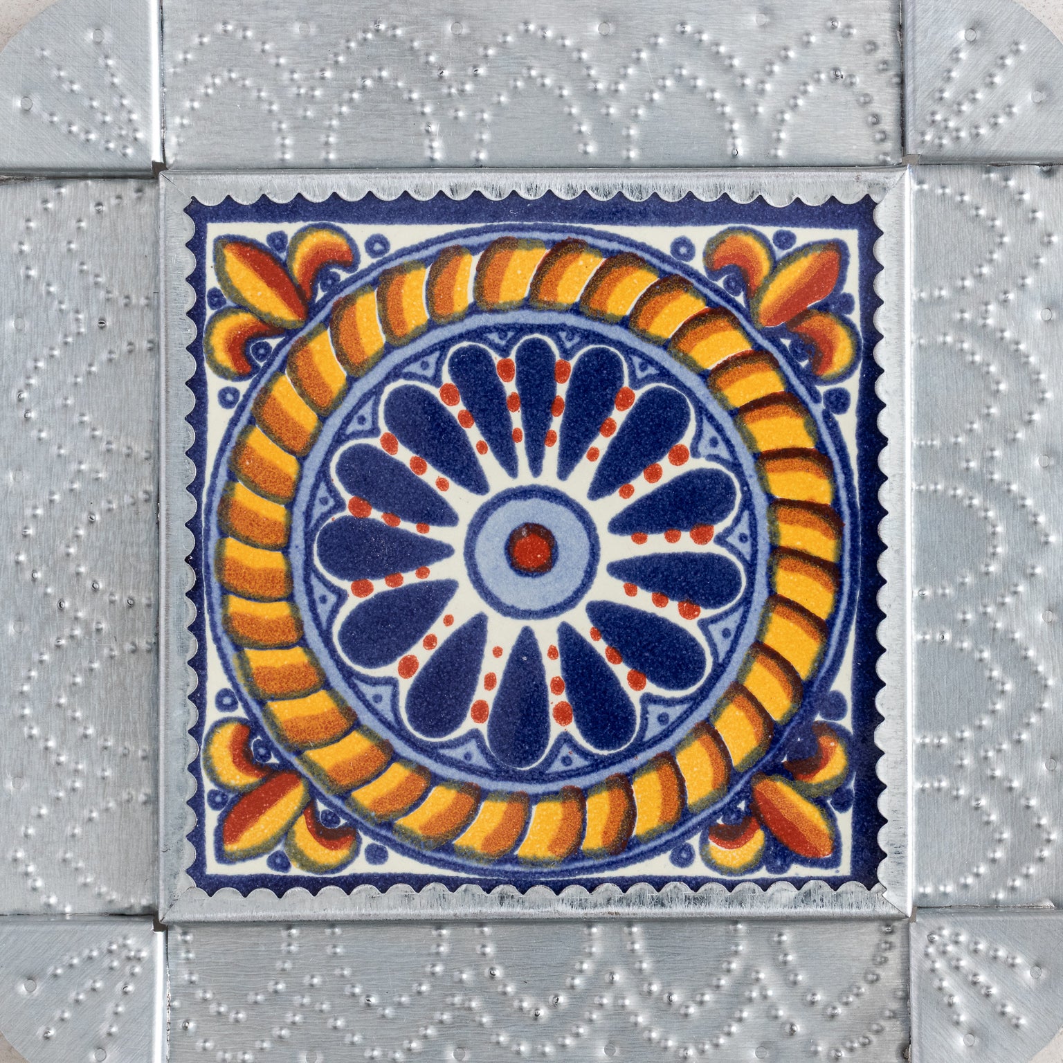 Decorative tinwork framed tile with a blue and orange circular pattern on a gray tiled background