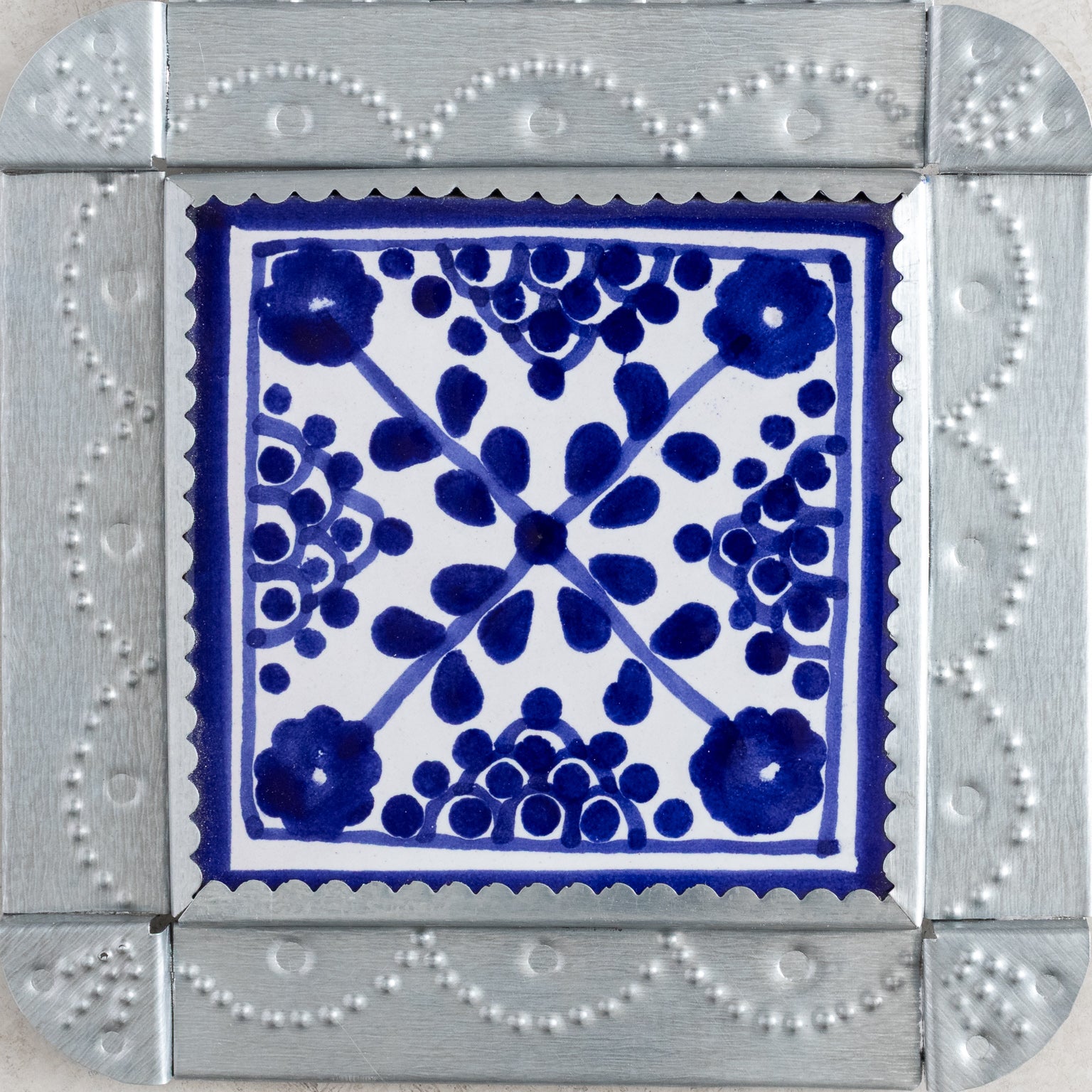 Closeup of a decorative tiwnork framed tile with blue floral pattern on a white background