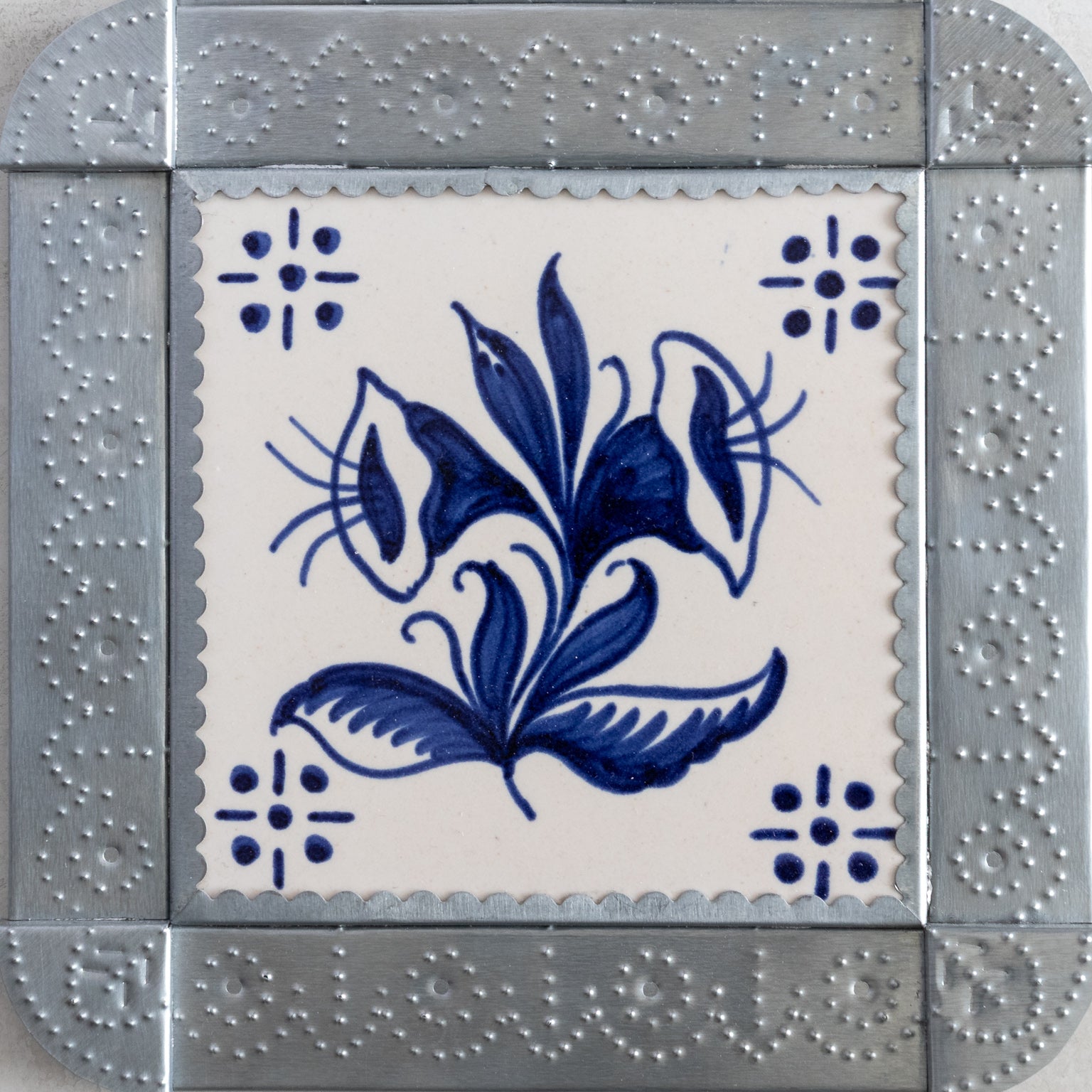 Closeup of a decorative tile with blue floral design on a white background