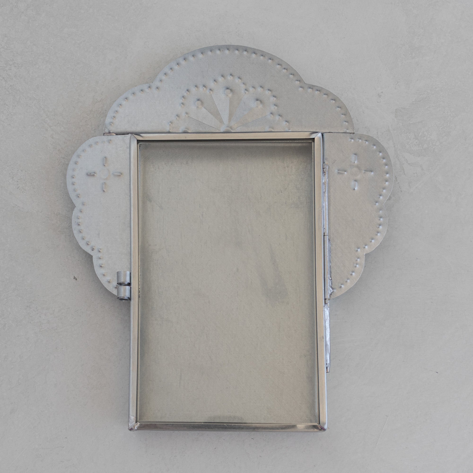 Nicho Postal front view, door closed, showing full cloud crest form, hand-punched fan motif, glass door, and hinge in natural tin.