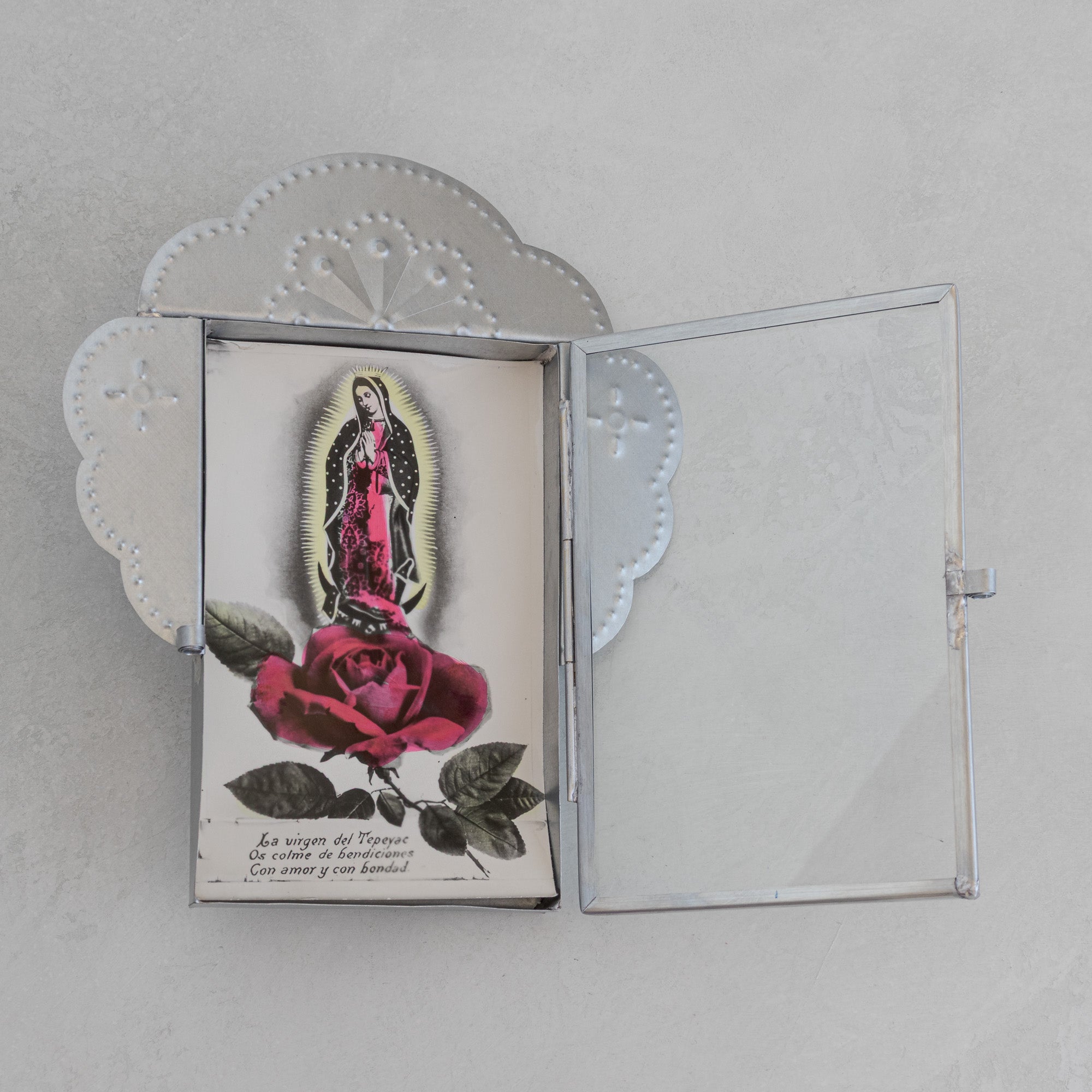 Nicho Postal open at an overhead angle holding a vintage Mexican postcard of La Virgen del Tepeyac with a red rose, natural tin cloud crest form visible above.